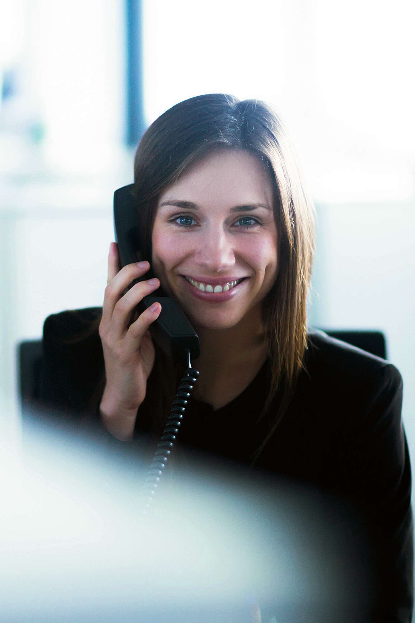Shot of pretty young woman using her mobile phone while working with laptop sitting on the floor at home.